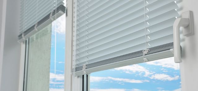 Close View Of White Blinds. Blue Sky In Background.