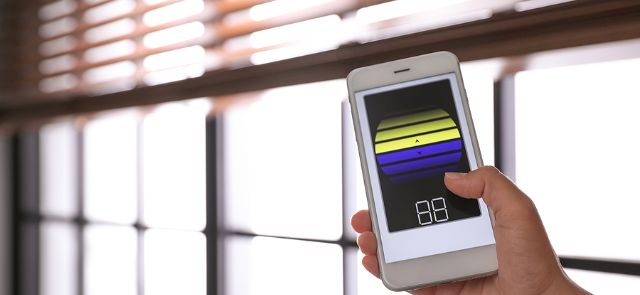 Woman Using Smart Phone To Control Blinds