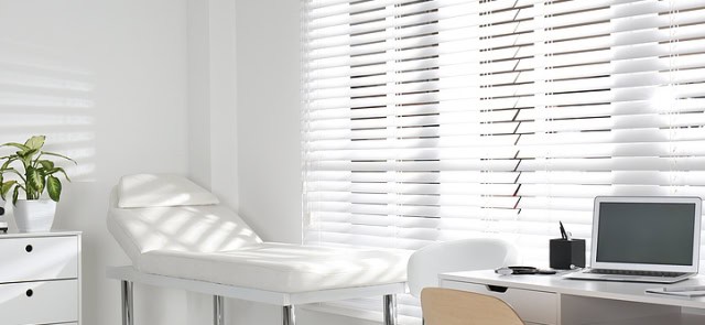 White Chaise Along A Window With White Blinds Letting In The Sun.