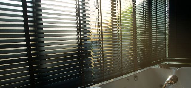 A Window With Blinds Allowing A Little Bit Of Light Through.