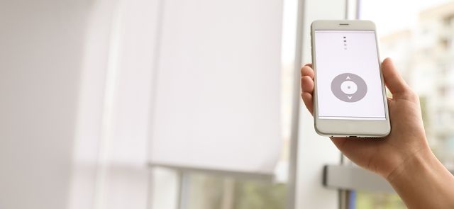 Someone Using An App On Their Phone To Control Motorized Shades.